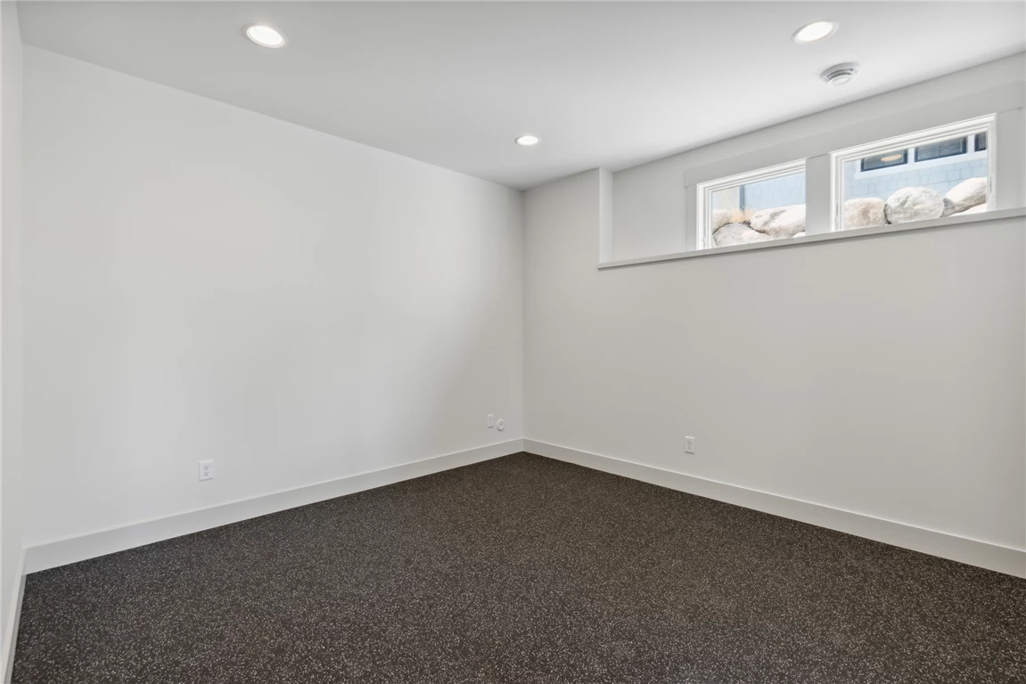 Interior view of a contemporary minimalist bedroom with parquet flooring and large windows.