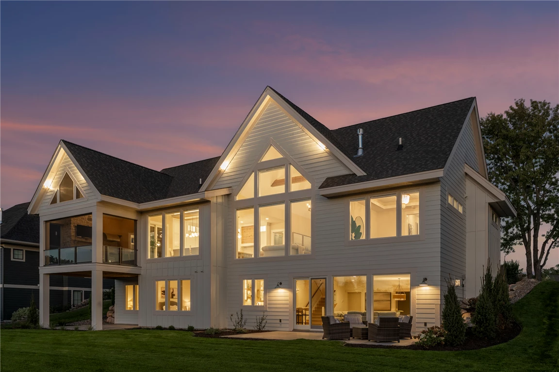 Rear angle view of a luxury suburban home with a spacious driveway and well-maintained lawn.