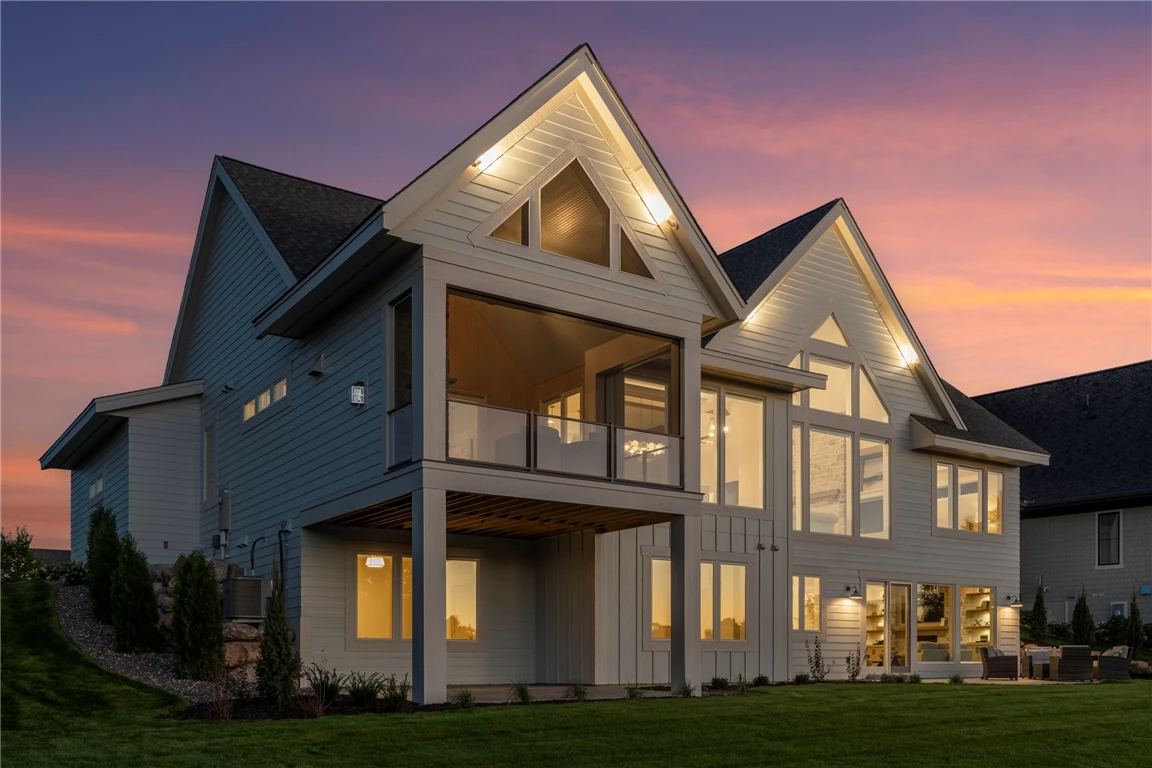 Rear angle view of a luxury suburban home with a driveway and lawn.