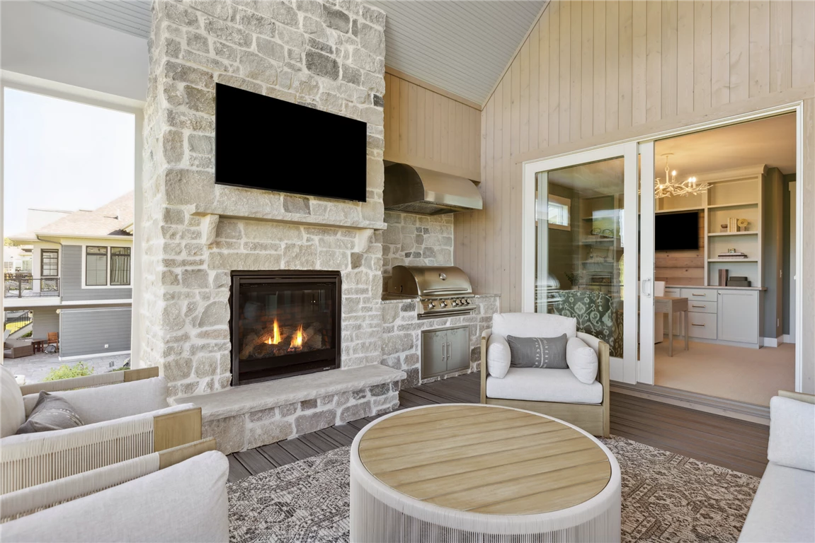 Contemporary family room with fireplace in a four-season porch, featuring modern furniture and large windows.