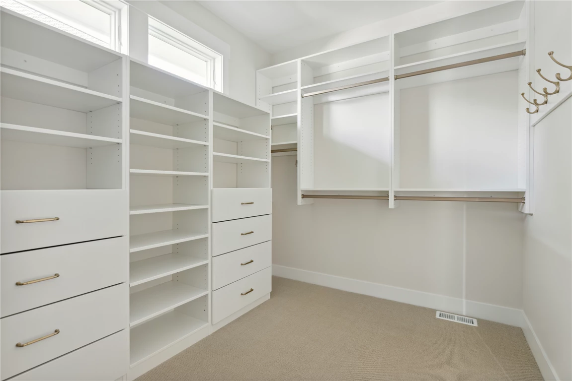 Contemporary minimalist master closet with cabinets and drawers.