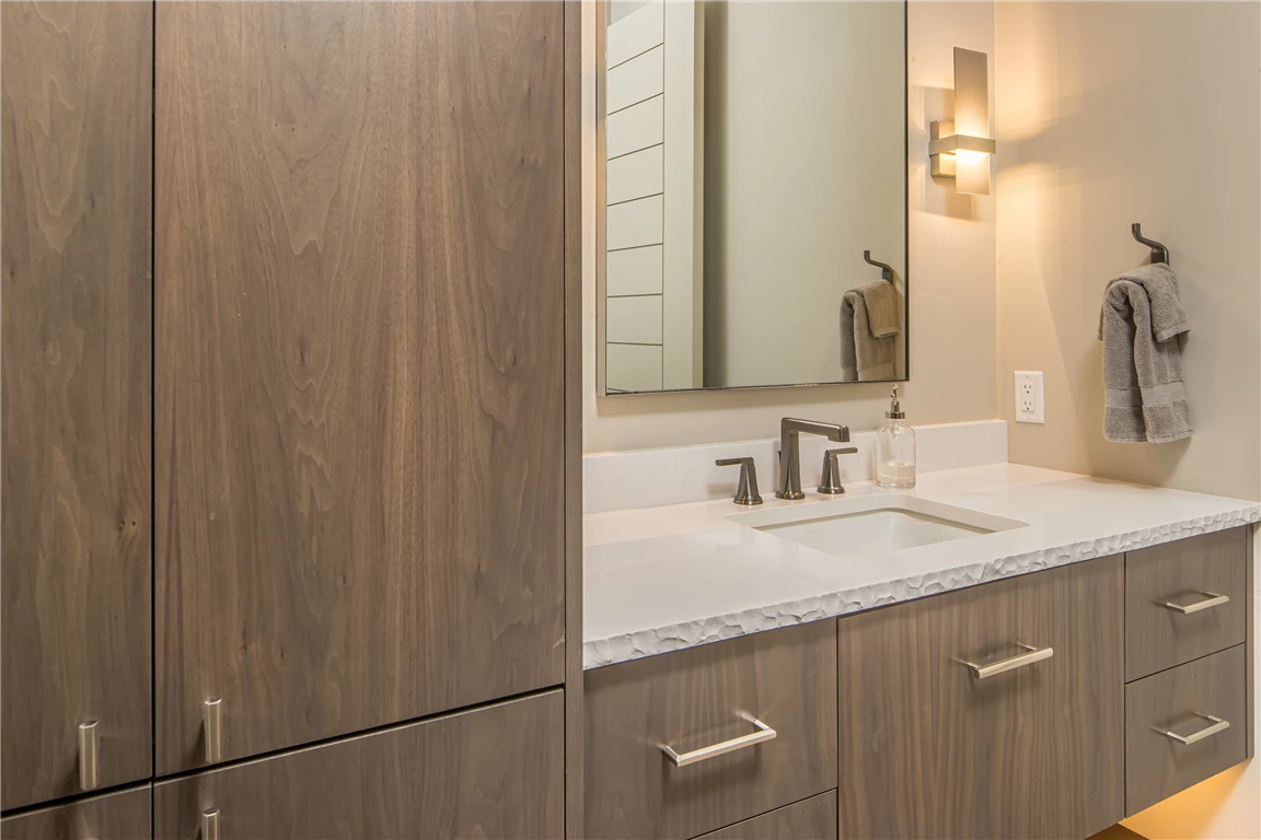 Contemporary luxury bathroom with wooden cabinet and large mirror.