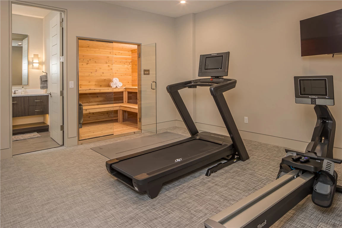 Contemporary home exercise room with treadmill and modern furniture.