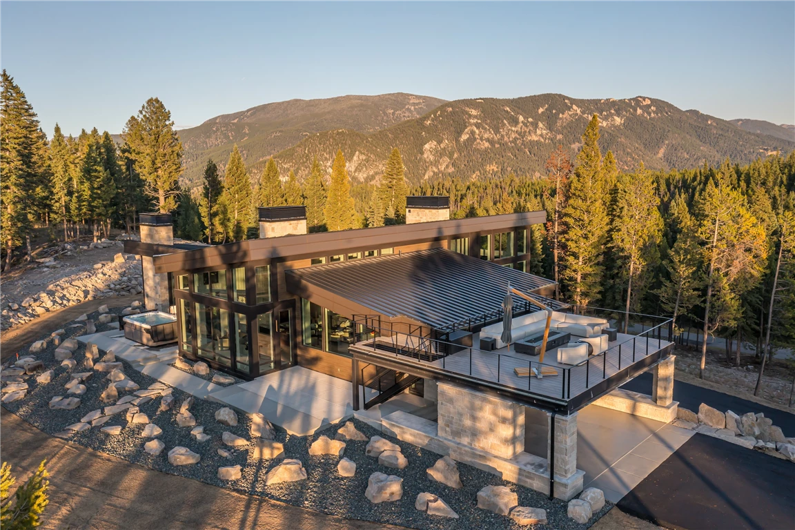 Golden hour view of a lake with mountains and a luxurious house.