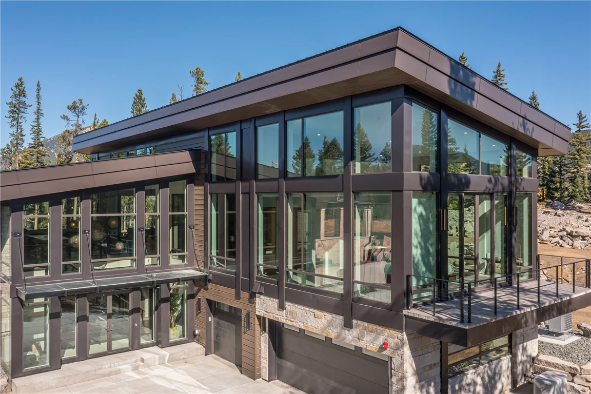 Exterior view of a modern luxury home with large glass windows and wood accents.