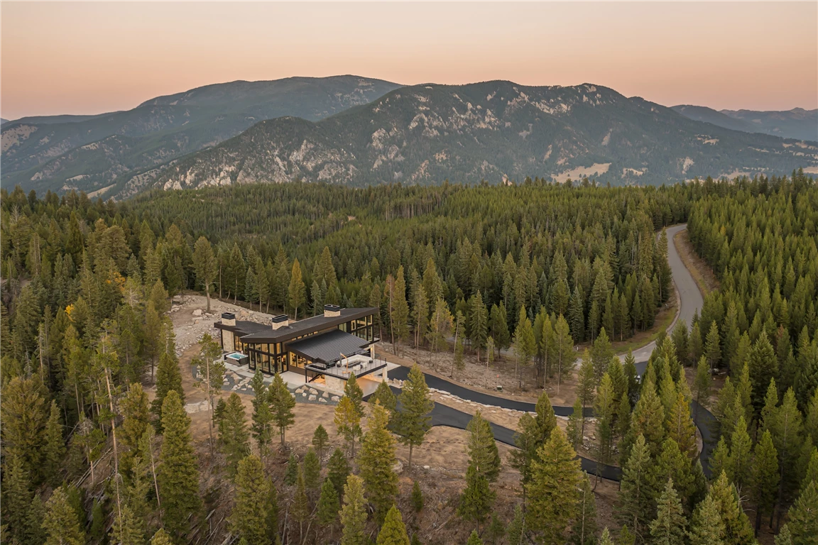 Scenic view of a mountain lake at sunset with evergreen trees and snow-capped mountains.