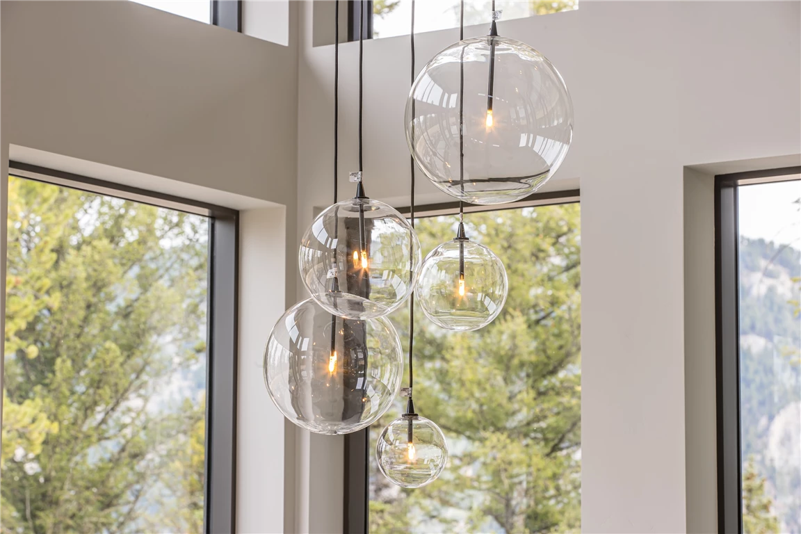 Contemporary indoor lighting with a view of a snowy winter landscape through a large window.