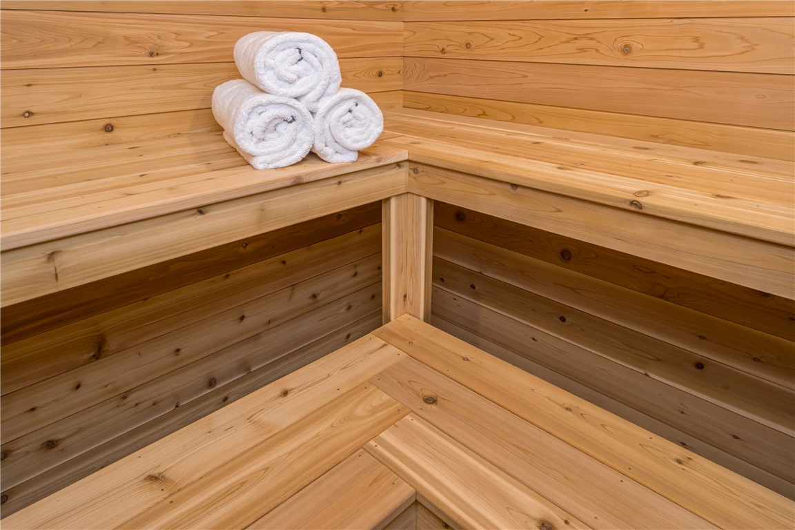 Interior view of a rustic wooden sauna with parquet flooring and wooden walls.