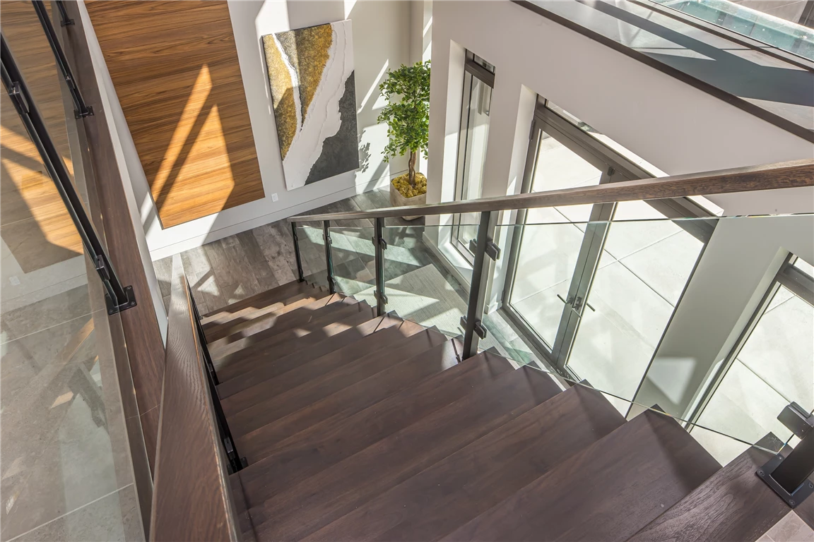 Modern luxury hotel staircase with wooden steps and glass handrail.